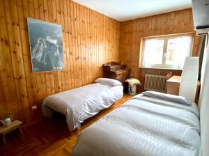 two beds in a room with wood paneling at Ceda Ladina in Santo Stefano di Cadore