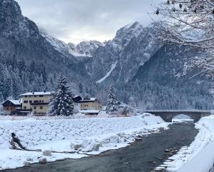 a snow covered river with a bridge and mountains at Ceda Ladina in Santo Stefano di Cadore