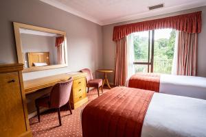 a hotel room with two beds and a desk and a mirror at Lakeside International Hotel in Camberley