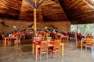 a restaurant with wooden tables and chairs in a room at Hlane Royal National Park in Simunye