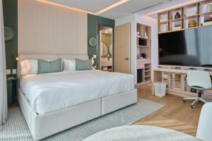 a bedroom with a large white bed and a television at WorldHotels Guadalajara Zona Andares in Guadalajara
