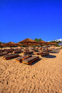 a beach with many chairs and umbrellas on it at Helios Beach Hotel & Bungalows in Karpathos