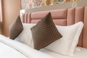 a bed with white pillows and a pink headboard at Cherrywood at Rajpur Road by Zenvana in Dehradun