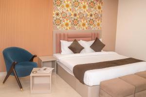 a bedroom with a bed and a blue chair at Cherrywood at Rajpur Road by Zenvana in Dehradun