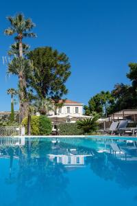 a large swimming pool with blue water and palm trees at Hôtel Château de la Tour Cannes in Cannes