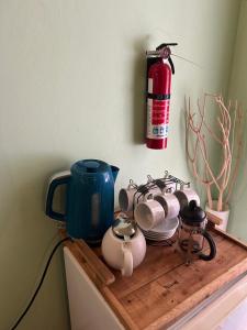 a shelf with pots and pans and a fire extinguisher at Soufriere Guesthouse in Soufrière