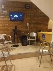 a room with chairs and a tv on a brick wall at Hospedagem Terral Beach Canoa Quebrada in Aracati