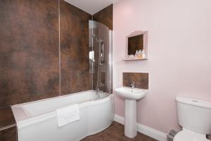 a bathroom with a tub and a sink and a toilet at Sandfordarms in Appleby