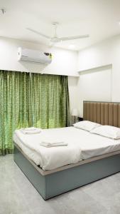a bed in a bedroom with a green curtain at CozyKey Kalina in Mumbai