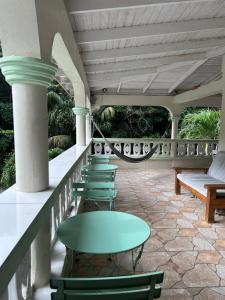 a row of green tables and chairs on a balcony at Soufriere Guesthouse in Soufrière