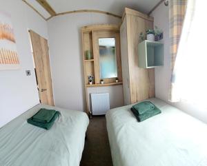 two twin beds in a room with a window at Thurston Manor Holiday Park - Woodlands 1 in Innerwick