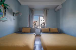 two beds in a room with a window at Lola's House in Ha Long