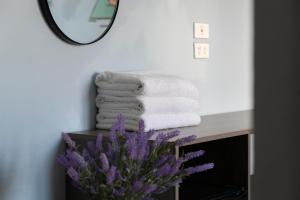 a bathroom with towels and a mirror and purple flowers at Lola's House in Ha Long +46 photos