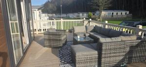 a patio with a couch and chairs on a deck at Thurston Manor Holiday Park - Woodlands 1 in Innerwick