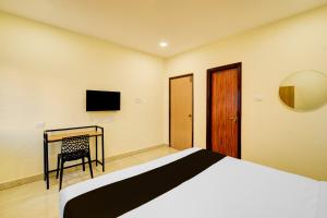 a bedroom with a bed and a desk and a television at Super Hotel O Nivara in Hyderabad
