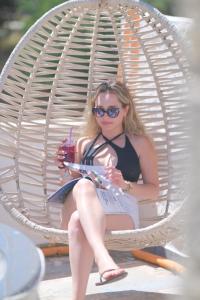 a woman sitting in a wicker chair holding a drink at Alacati Naz Konak in Çeşme