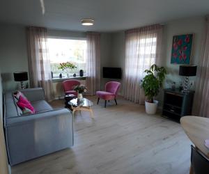 a living room with a gray couch and pink chairs at De Sas in Lisse in Lisse