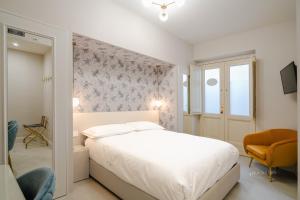 a white bedroom with a bed and a chair at Piazza Duomo Guest House in Ariano Irpino