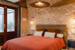 a bedroom with a red bed with a stone wall at Habitació EL GRANER in Rasquera