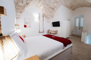 a bedroom with a large white bed and a tv at Filo Rosso in Ostuni