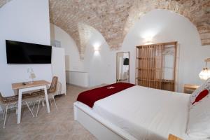 a bedroom with a bed and a table and a tv at Filo Rosso in Ostuni