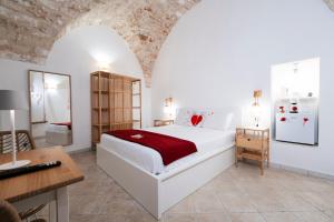 a bedroom with a bed and a desk in a room at Filo Rosso in Ostuni