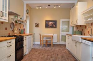 a kitchen with white cabinets and a table at Dunmore Argyll House in Dunoon