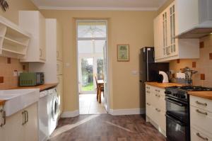 a kitchen with white cabinets and an open door at Dunmore Argyll House in Dunoon
