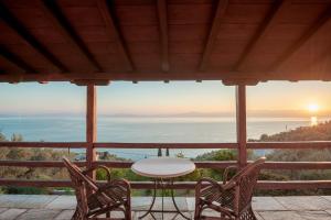 a table and chairs on a porch with a view of the ocean at Cypresses Villas in Áno Gatzéa