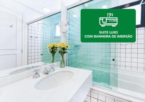 a bathroom with a sink and a green sign at Hotel Nacional Inn Cambuí Campinas Residence in Campinas +48 photos