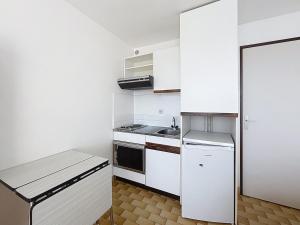 a small white kitchen with a stove and a refrigerator at Studio 4 pers La Lagune in Le Grau-du-Roi