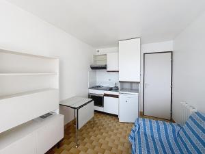a small white kitchen with a bed and a table at Studio 4 pers La Lagune in Le Grau-du-Roi