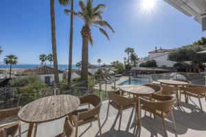 a patio with tables and chairs and a view of the ocean at Stunning 5-Bed Villa with Private Pool in Manilva