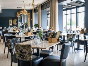 a restaurant with tables and chairs and a chandelier at Quality Hotel Grand Larvik in Larvik