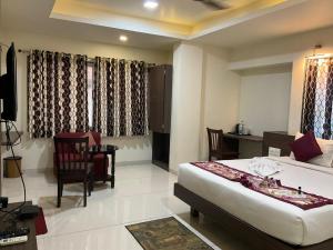 a bedroom with a bed and a table and chairs at The Hotel Relax in Kankauli