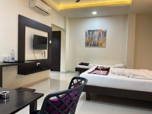 a hotel room with a bed and a table and chair at The Hotel Relax in Kankauli