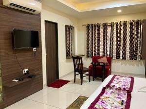 a hotel room with a bed and a chair and a television at The Hotel Relax in Kankauli