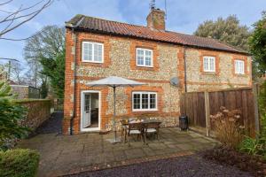a brick house with a table and an umbrella at Rose Cottage in Docking