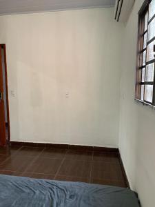 a room with a bed and a white wall at Casa para MotoGP in Goiânia