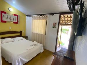 a bedroom with a bed and a tv and a window at Pousada Embaubas in Serra do Cipo