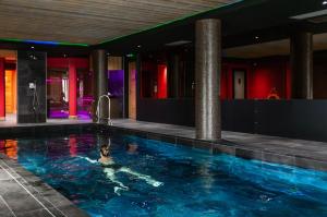 a person swimming in a pool in a building at Hôtel Daria-I Nor by Les Etincelles in L'Alpe-d'Huez