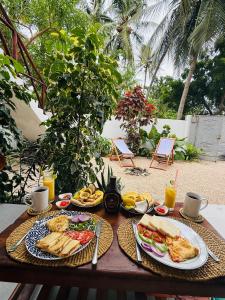 a table with plates of food and drinks on it at Peace and Love Villa in Jambiani