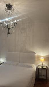 a white bedroom with a bed and a chandelier at Luxury Apartment in Moltrasio Center in Moltrasio