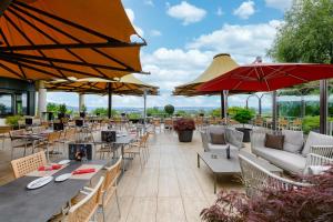 a restaurant with tables and chairs and umbrellas at Mövenpick Hotel Egerkingen in Egerkingen