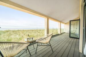 a room with a balcony with chairs and a table at Washington Beach House in Heacham
