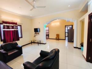 a living room with two chairs and a tv at MG Elite Residency in Pondicherry