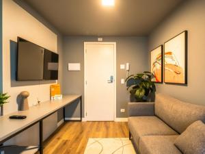 a living room with a couch and a tv at Easy Life Campus PUC by Xtay - Estúdio completo próximo PUCPR in Curitiba