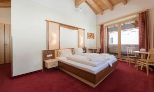 a bedroom with a bed and a large window at Hotel Abendrot by Alpeffect Hotels in Ischgl