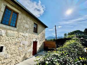 a stone house with a red door and some flowers at Mont Pellat - Spacieux studio au Charme Unique in Bassens