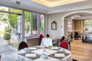 a restaurant with tables and chairs and windows at Hôtel Château de la Tour Cannes in Cannes